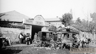 La imagen de 1906 nos muestra los carruajes (taxis de la época) que esperaban a los pasajeros en la Estación del Llano de Maipo. Esta estación rural se encontraba en lo que es el Parque Bustamante con Plaza Italia. Fue demolida en 1907 y se construyó la antigua Estación Pirque, hoy también demolida. La fotografía nos muestra las precarias condiciones de la Estación, como también de los carruajes, viejos y sucios. Los caballos se notan famélicos, mal alimentados y nunca cepillados. La humedad y el barro, era muy común en la mayoría de Santiago en esa época. El presidente de la época era don Germán Riesco Errázuriz. Un año de terremotos y tifus que diezmo a la población chilena.