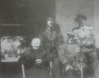 En la imagen podemos ver a Don Juan Oliveros Avila, en el portal de su casa, frente a la municipalidad de Yerbas Buenas, vestido con el glorioso uniforme de la Guerra del Pacífico, portando en sus manos su querido sable. Junto a él, su esposa Doña Margarita Lara Alfaro y atrás sus dos hijos. Cuando falleció un años después en 1951, fue enterrado con su uniforme y con todos los honores militares. /Fecha de la imagen: 19 de septiembre de 1950.